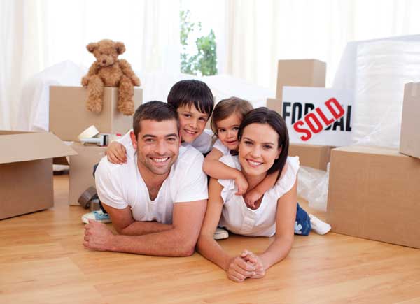 smiling family on floor surrounded by empty moving boxes.